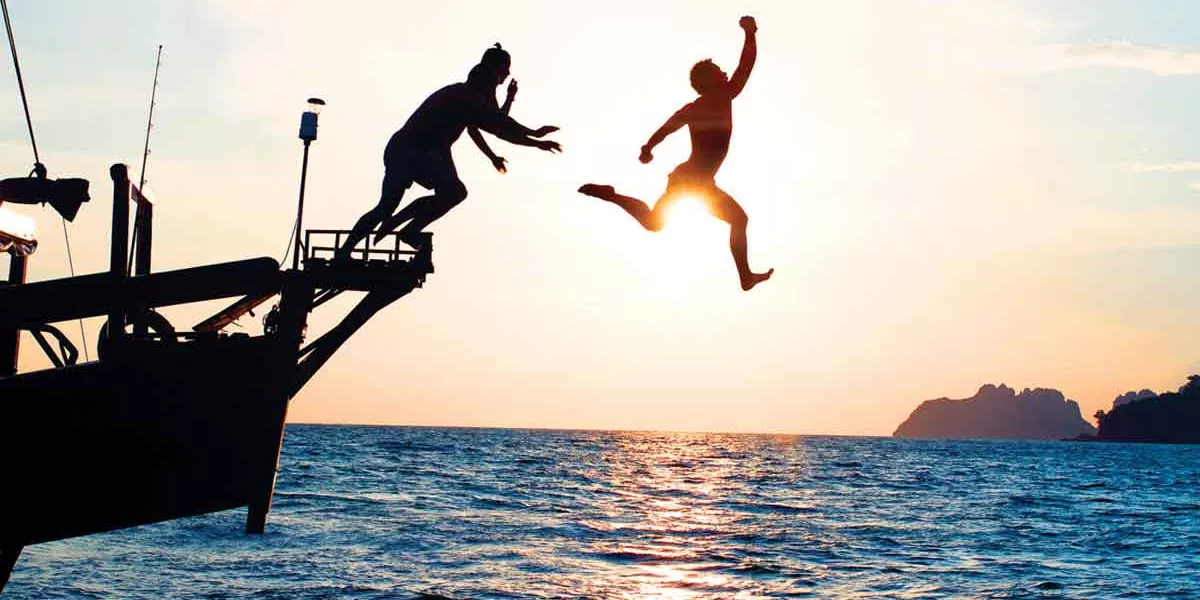 Group Jumping Into The Sea In Thailand At Sunset