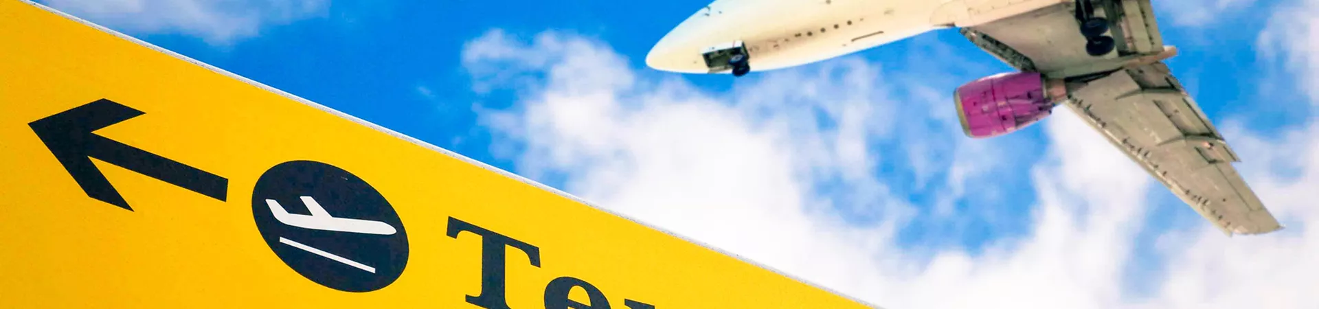 Airplane Flying Over Airport Sign Blue Sky